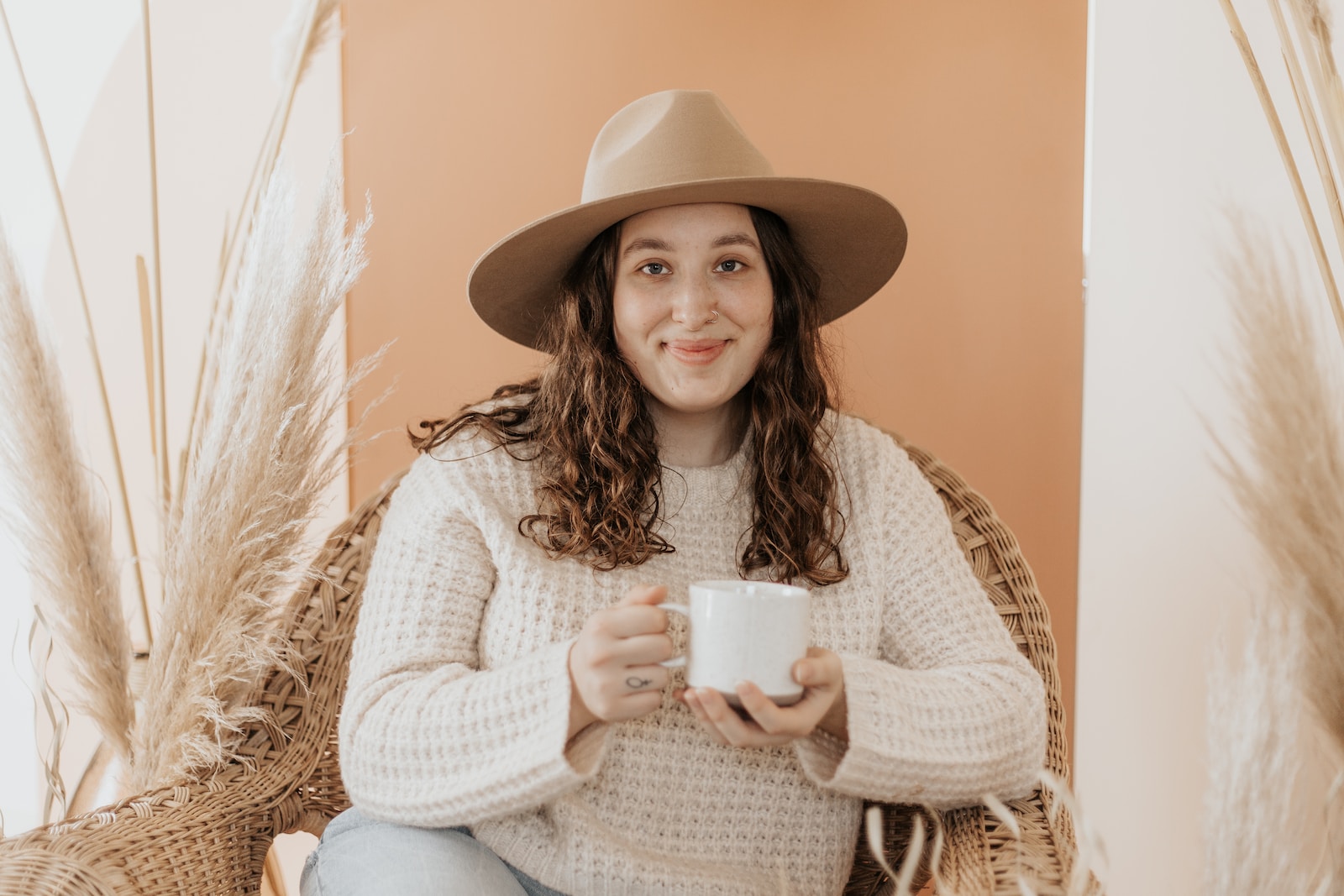 woman in white knit sweater holding white ceramic mug